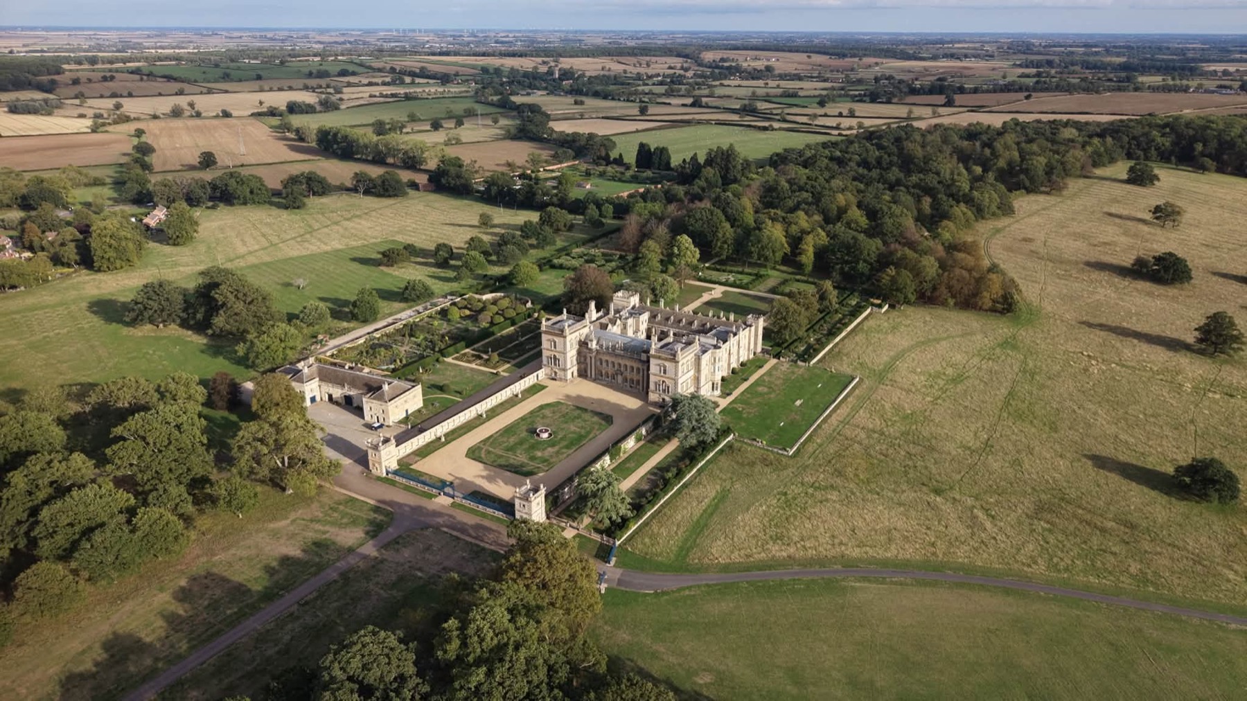 Aerial view of a country house, formal gardens and surrounding parkland
